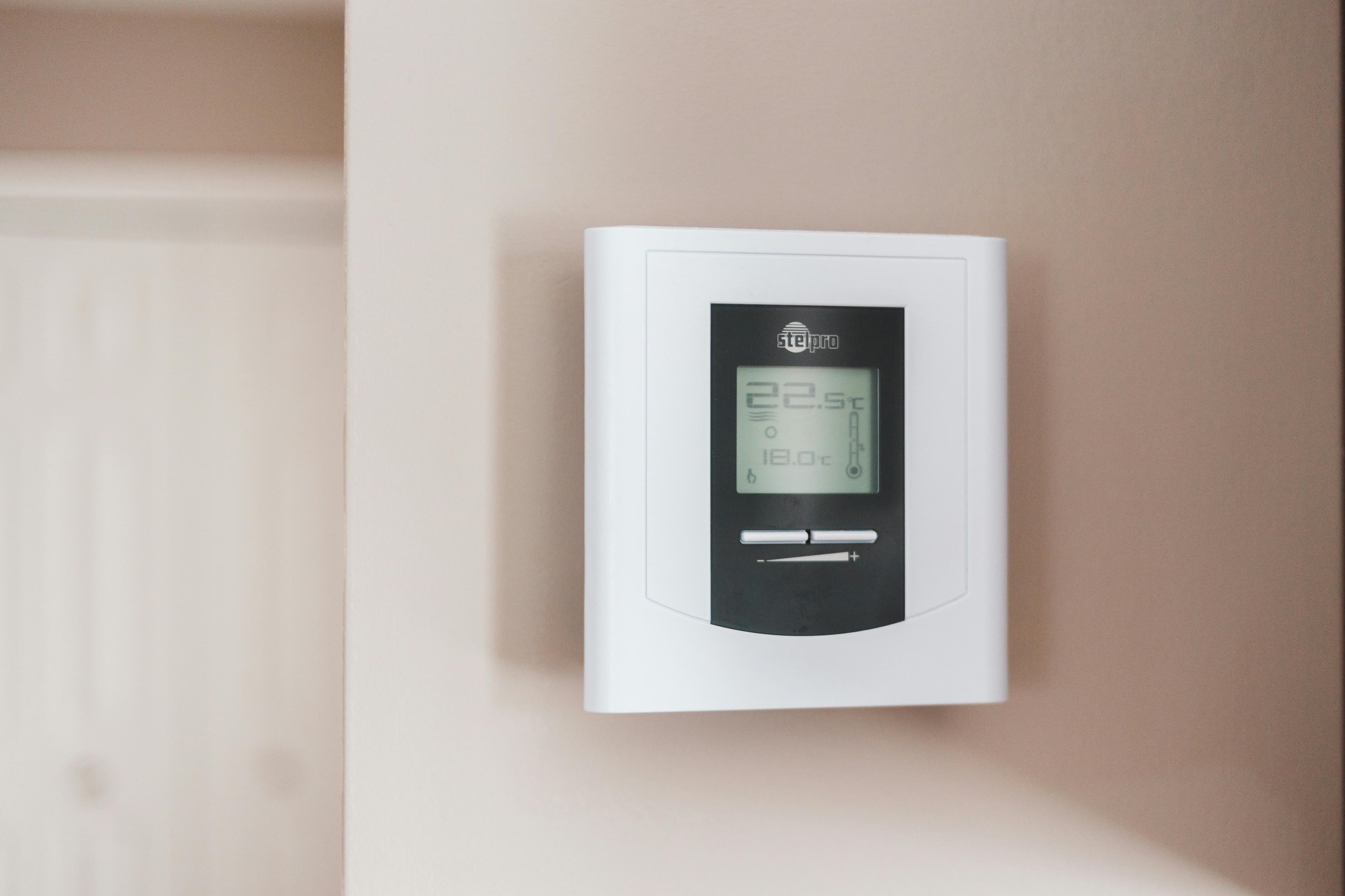 Thermostat and indoor wall representing AC repair and cooling control